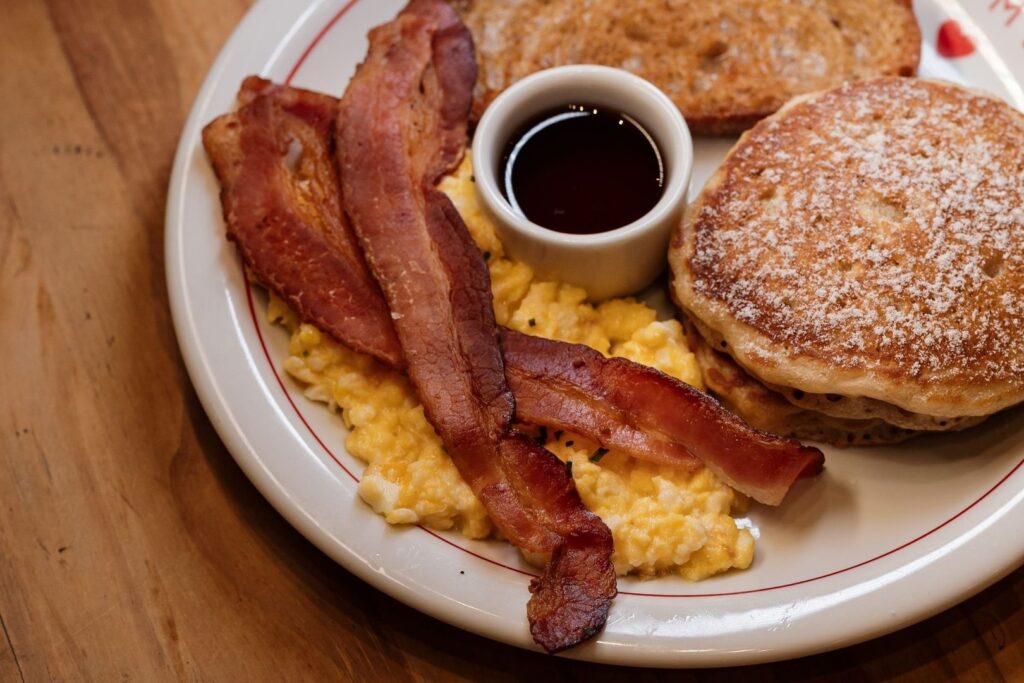 Classic diner breakfast with pancakes, bacon, eggs, and syrup