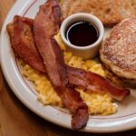 Classic diner breakfast with pancakes, bacon, eggs, and syrup