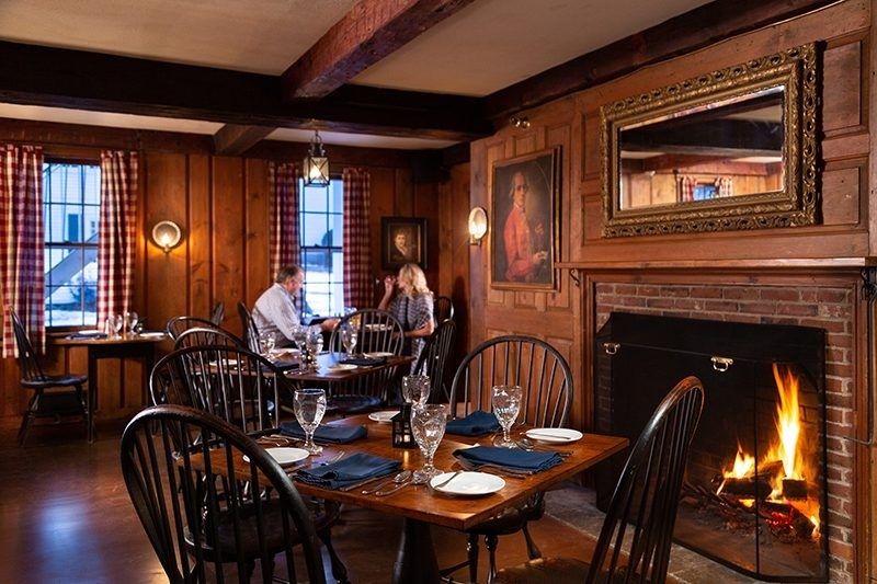 Cozy wood-paneled restaurant dining room with a glowing fireplace