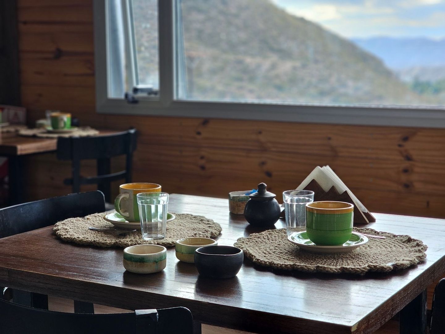 Cozy wooden dining table set with coffee and tea beside a mountain view