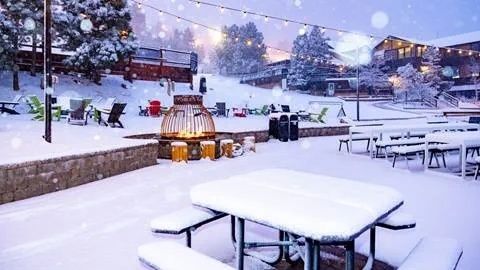 Snow-covered outdoor dining area with picnic tables and string lights